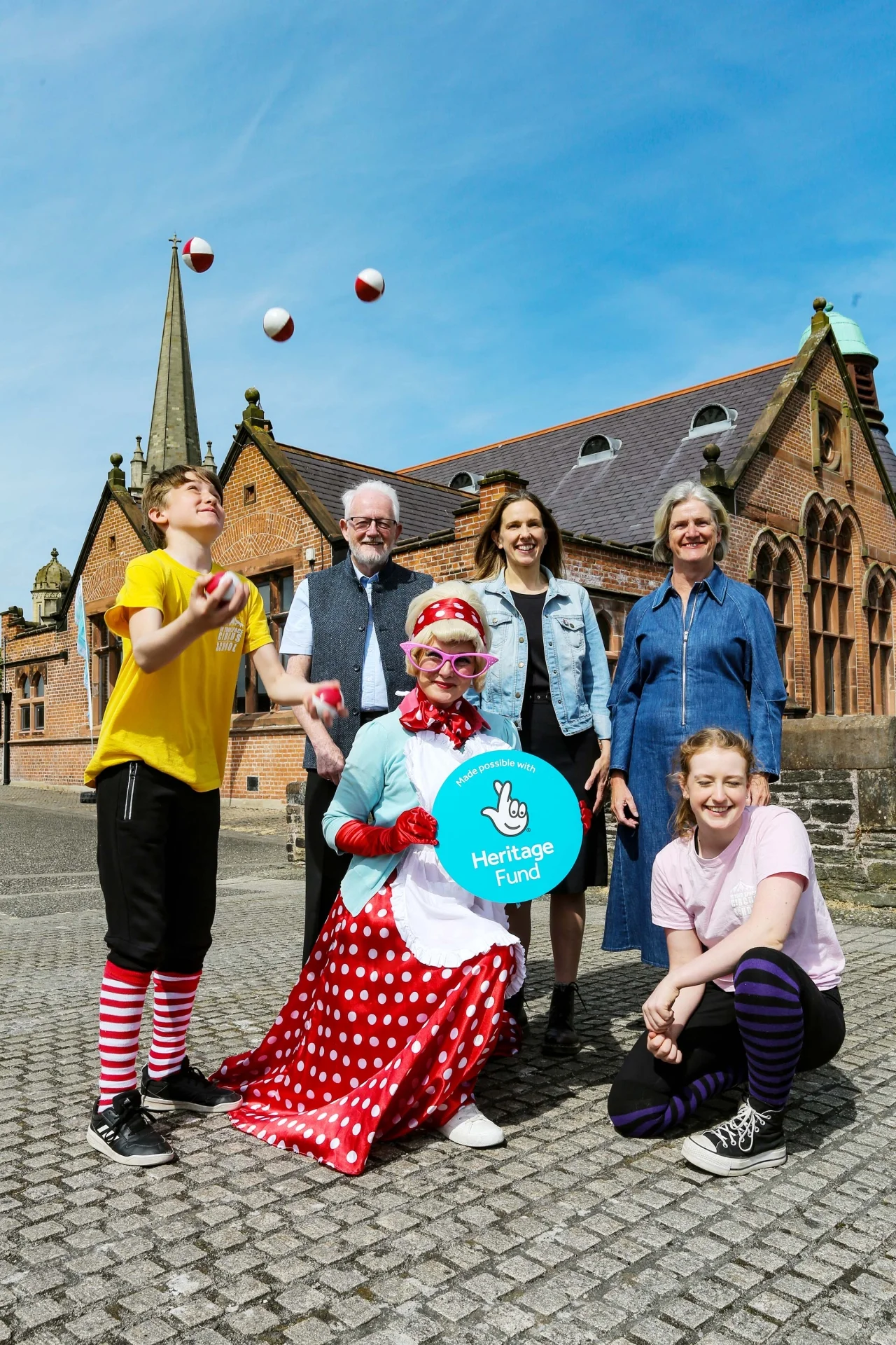 Group pose for a photo on the city walls beside the Cathedral School holding a Heritage Lottery sign